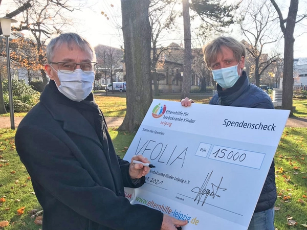 Laurent Hequet, Veolia-Geschäftsführer des Bereichs Wasser, signiert den symbolischen Spendenscheck an Markus Wulftange, Sporttherapeut des Elternhilfe für krebskranke Kinder Leipzig e. V., Foto: Elternhilfe für krebskranke Kinder Leipzig e. V. 