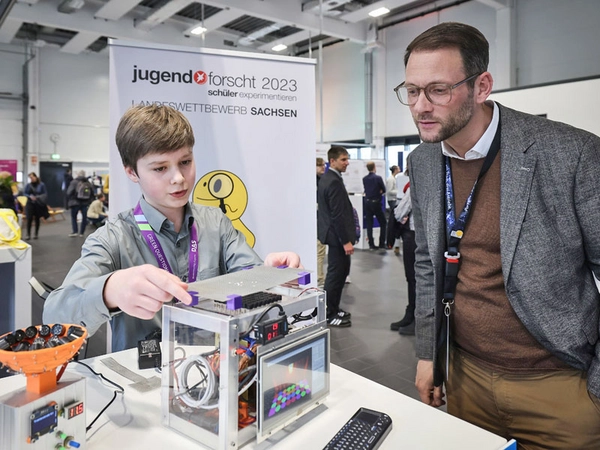 Landessieger Eneko Reichert Vicario (14) erklärt Ruven Weichert, kaufmännischer Geschäftsführer der Porsche Leipzig GmbH, sein Projekt „Manipulation von Objekten mittels akustischer Levitation“. Foto: Porsche AG - Leipzig