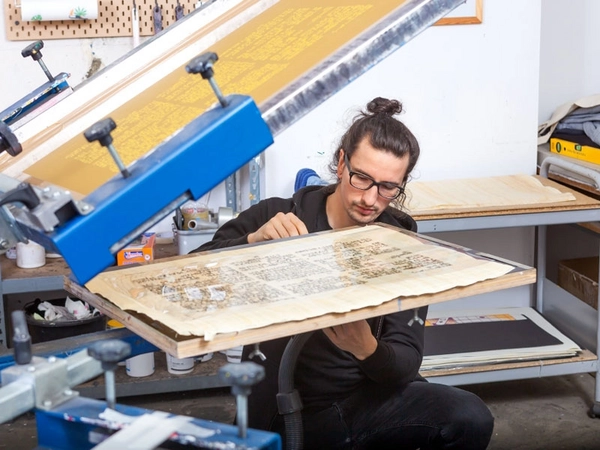 Dennis Blumenstein bei der aufwändigen Herstellung der Replik des Papyrus Ebers per Siebdruckverfahren in der Leipziger Werkstatt von Schmidt, Blumenstein GbR, Foto: Universität Leipzig / Swen Reichhold