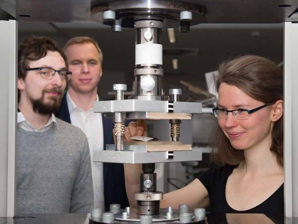 Nachwuchsgruppenleiter Florian Wallburg, Professor Stephan Schönfelder und Doktorandin Ulrike Käppeler (v.l.n.r.) an einer Prägemaschine im Werkstofflabor der HTWK Leipzig, Foto: Lizette Ardelean / HTWK Leipzig