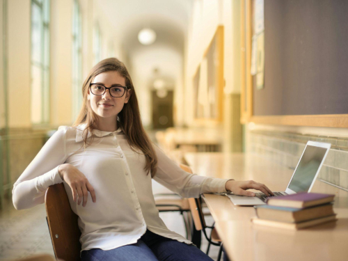 Eine Studierende arbeitet mit Laptop und Büchern in der Hochschule – Symbol für gute Organisation und konzentrierte Vorbereitung auf die Abschlussphase.