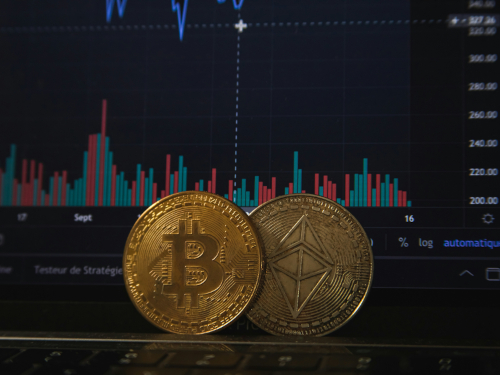 Bitcoin- und Ethereum-Münzen vor einem Bildschirm mit Kryptowährungs-Kursdiagramm. Foto: unsplash.com / peiobty