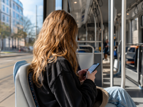 Junge Frau nutzt ihr Smartphone in einer Straßenbahn